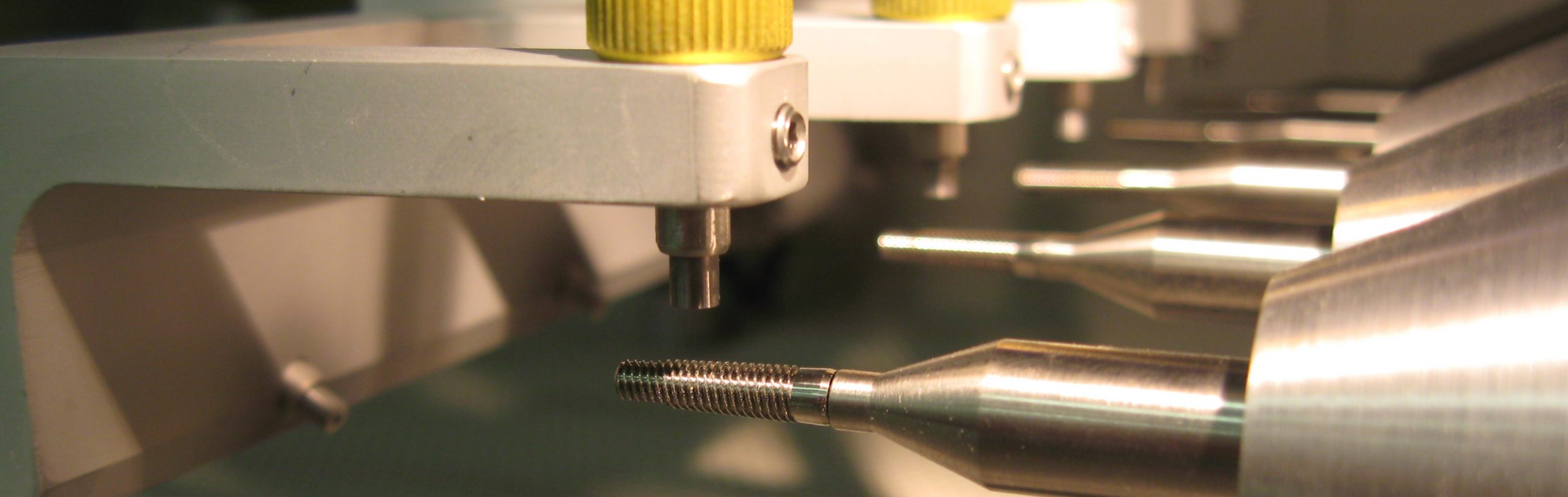 Dental implants being textured in Comco's Advanced Lathe MicroBlasting System